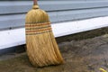 Old obsolete broom made of broom sorghum or a broom, leaning on a gray wall. Housekeeping by means of manual labor