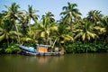 Old ocean fishing boat along the canal Kerala backwaters shore with palm trees between Alappuzha and Kollam, India Royalty Free Stock Photo