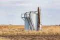 Old oil well storage tanks in farm field.