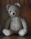 Old one-eyed teddy bear against wooden furniture, close-up shot Royalty Free Stock Photo