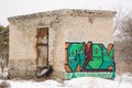 Old one-story brick building a rusty door with graffiti on wall