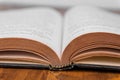 Old open book on a wooden table. White background. closeup