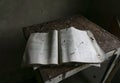 An old open physics book over a rusty and old table inside an abandoned house at chernobyl radioactive exclusion zone