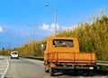 Old orange farm utility vehicle - truck on paved country road in Greece driving to the side so someone can pass Royalty Free Stock Photo