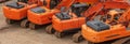 Old orange heavy excavators parked in one row