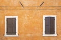 Old orange house facade, closed brown window shutters in popular touristic historic village Garda Royalty Free Stock Photo