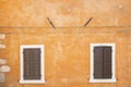 Old orange house facade, closed brown window shutters in popular touristic historic village Garda Royalty Free Stock Photo