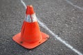 Old orange striped cone on road.