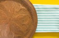 Old oriental copper dish on blue striped folded towel and yellow background.