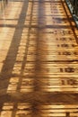 Old ornate railings casting a sunlit shadow on worn wooden parquet balcony flooring