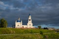 an old Orthodox church and a village on the river bank.sunset sun and black clouds. Royalty Free Stock Photo