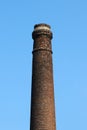 An old and out-of-use brick industrial plant chimney against a blue clear sky Royalty Free Stock Photo