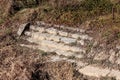 Old outdoor stairs made from stone and concrete on side of river bank covered with dense overgrown grass and layer of dust Royalty Free Stock Photo