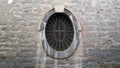 Old oval window with a metal grille set in a stone wall Royalty Free Stock Photo