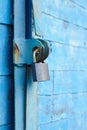 old padlock on a blue metal door with wooden planks cracked paint and rust Royalty Free Stock Photo