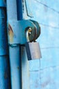 old padlock on a blue metal door with wooden planks cracked paint and rust Royalty Free Stock Photo
