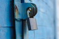 old padlock on a blue metal door with wooden planks cracked paint and rust Royalty Free Stock Photo