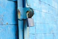 old padlock on a blue metal door with wooden planks cracked paint and rust Royalty Free Stock Photo