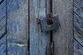 An old padlock on a blue stripped wooden gate. Protect property and privacy. Close-up Royalty Free Stock Photo