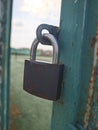 Old padlock on the net fence gate Royalty Free Stock Photo