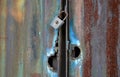 An old padlock on a rusty tin blue door already looted several times, a stolen garage, imperfectly secured with holes after autoge Royalty Free Stock Photo
