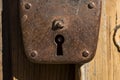 An old padlock rusty weighs on a wooden door.