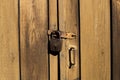 An old padlock rusty weighs on a wooden door.