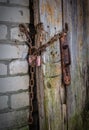 Old padlock on a wooden door. Wooden door locked with padlock close-up, focus on lock. Rusty padlock with chain on the door Royalty Free Stock Photo