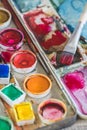 Old paintbox with watercolours. Vibrant colours used on the palette, brush with red paint Royalty Free Stock Photo