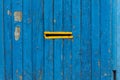 Old painted blue wooden fence with a yellow slit Royalty Free Stock Photo