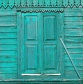 Old painted green wooden shuttered window on decorated wall