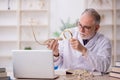 Old male paleontologist examining ancient animals at lab