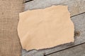 Old paper piece and burlap on wooden textured background Royalty Free Stock Photo