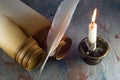 Old paper scroll, quill pen and burning candle in an old candlestick