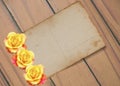 Old paper with yellow roses on the blue wooden background Royalty Free Stock Photo