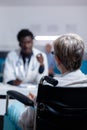 Old patient with disability receiving consultation from black medic