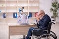 Old patient in wheel-chair visiting devil doctor Royalty Free Stock Photo