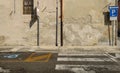 Old peeled plaster wall with a gutter on the middle. Road signs by sides. Concrete sidewalk and street in front