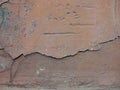 Old peeling red terracotta pink plaster on a cracked rough, scratched uneven concrete stone wall. Royalty Free Stock Photo