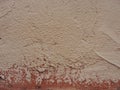 Old peeling red terracotta pink plaster on a cracked rough, scratched uneven concrete stone wall. Royalty Free Stock Photo