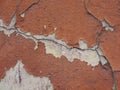 Old peeling red terracotta pink plaster on a cracked rough, scratched uneven concrete stone wall. Royalty Free Stock Photo