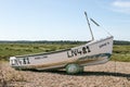 A old peeling sailing boat on a pebble boat