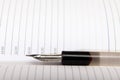 An old pen-holder with a pen lies on an open notebook. Close-up. Selective focus.