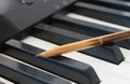 Old Pencil on Black Keys of Electric Piano in Crosswise View