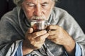 Old people senior man with winter seasonal illness fever cold problems drinking a pharmacy medicine or hot tea to go healthy -