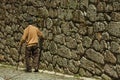 Old people walking down the alley on slope next to stone wall