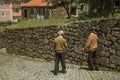 Old people walking down the alley on slope next to stone wall Royalty Free Stock Photo