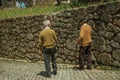 Old people walking down the alley on slope next to stone wall Royalty Free Stock Photo