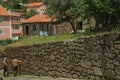 Old people walking down the alley on slope next to stone wall Royalty Free Stock Photo