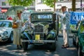 Old Peugeot and older couple at Classic Days, a Oldtimer automobile exhibition showing vintage cars and historic vehicles